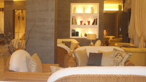A hotel room with a large bed, a sofa, a bookshelf with decorative items, and a mirror. - Residence Oliveto (Ceriale)