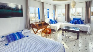 A hotel room with two beds, a desk, and a chair. There are curtains on the windows, and a painting on the wall. - La Estrella de Tarifa (Tarifa)