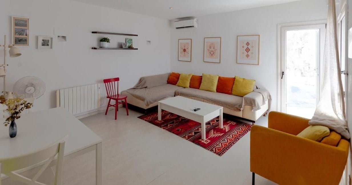 A modern living room with a sofa, a red chair, a white coffee table, and a red rug.