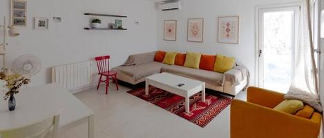 A modern living room with a sofa, a red chair, a white coffee table, and a red rug.