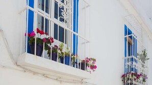 A white building with blue accents, featuring balconies with metal railings and flower boxes. - La Estrella de Tarifa (Tarifa)