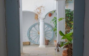A courtyard with a white column, a blue wheel, and potted plants. - La Estrella de Tarifa (Tarifa)