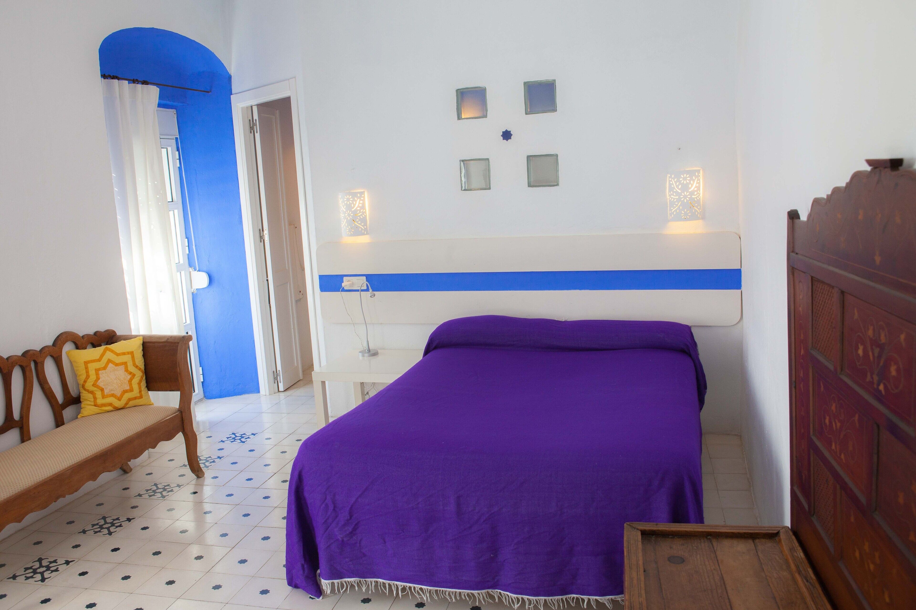 Un dormitorio con cama, un banco y una puerta.
