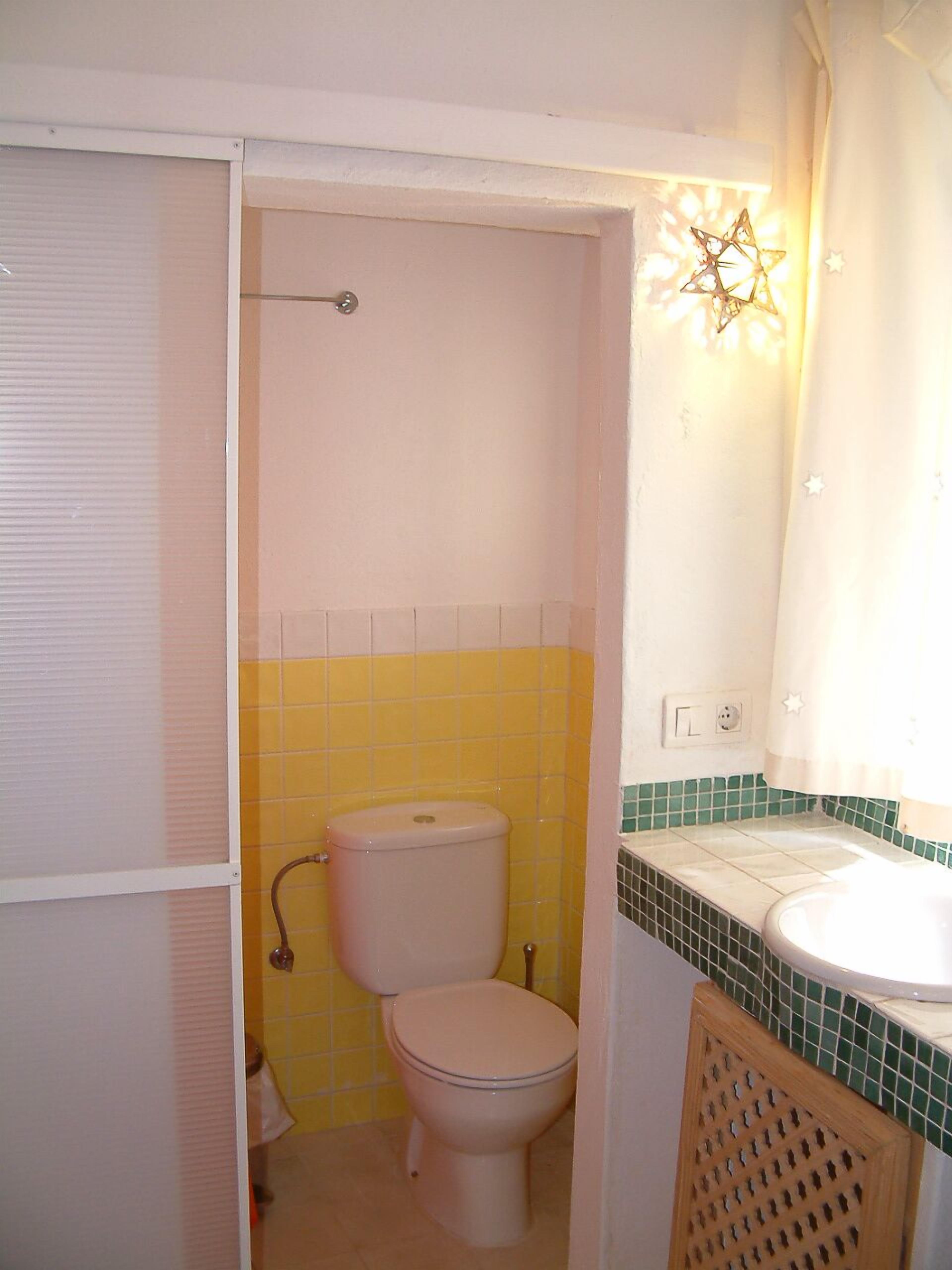 A compact bathroom with a toilet, sink, and a shower curtain.