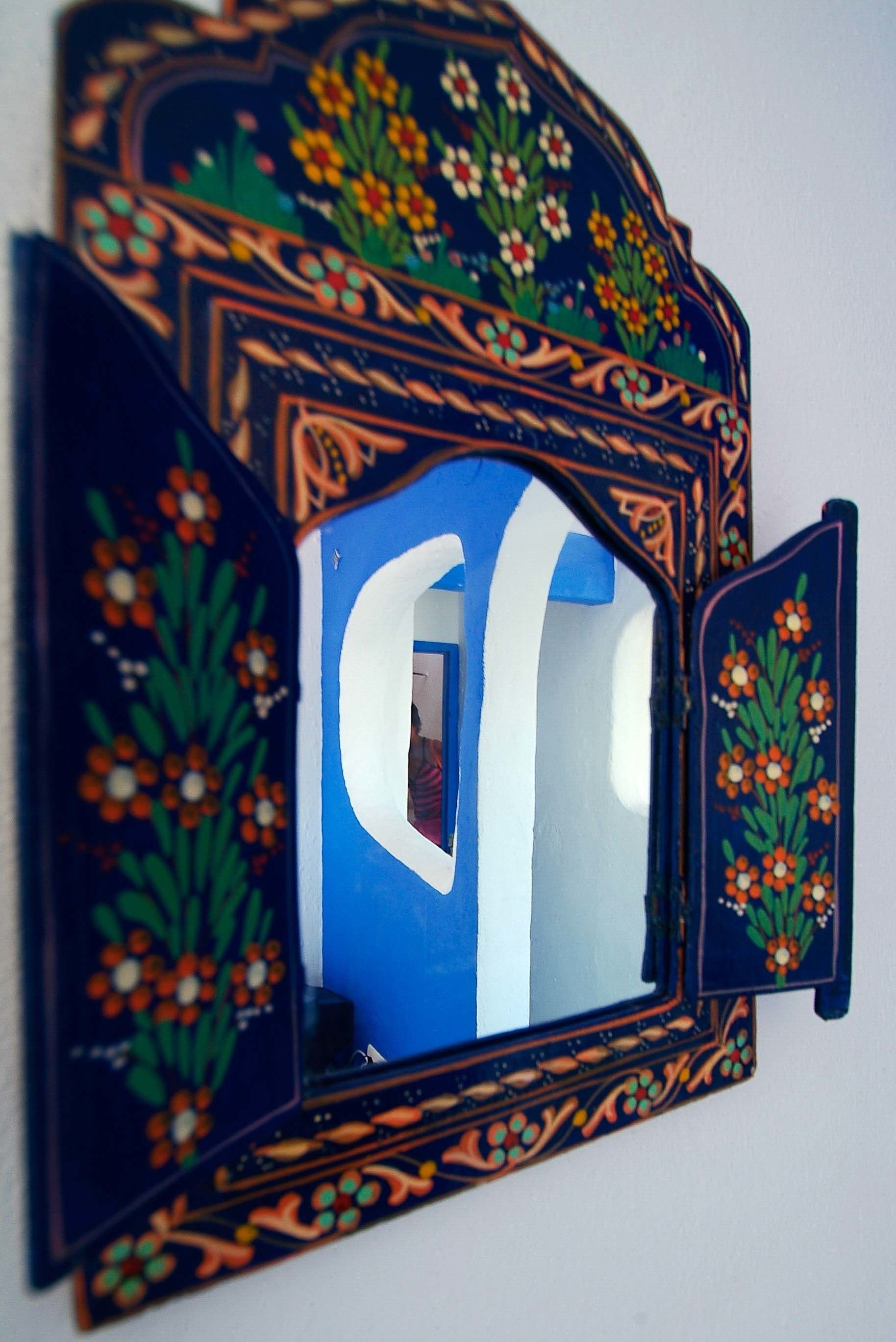 A decorative mirror with intricate floral patterns and a prominent letter 'C' in the center.