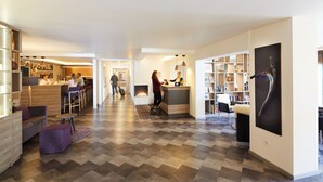 A hotel lobby with a reception desk, seating area, and a fireplace. - NaturKulturHotel Stumpf (Neunkirchen)