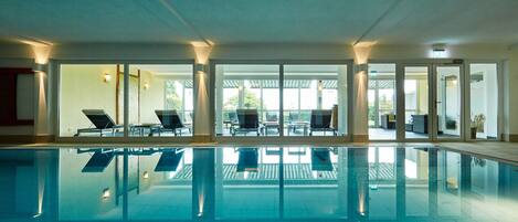 Una piscina techada, sillones reclinables de piscina