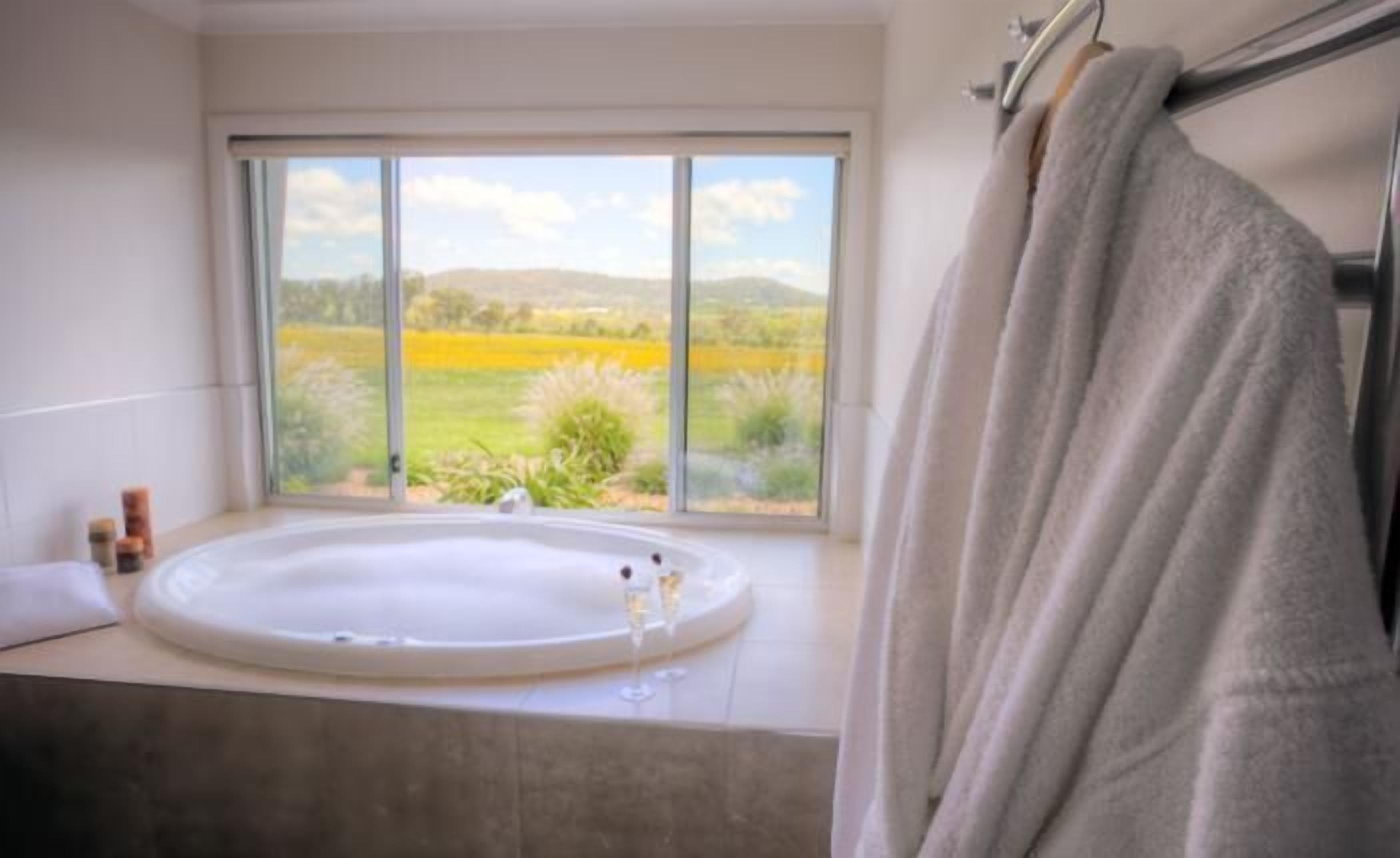A bathroom with a large window, a bathtub, and a towel rack.
