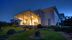 A modern house with a large covered patio, a well-maintained lawn, and a clear sky.
