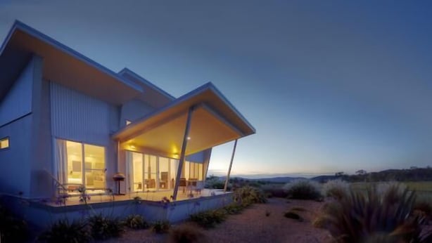 A modern house with a large porch and a view of the surrounding landscape.