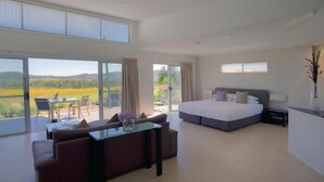 A spacious bedroom with a large bed, a glass dining table, and a sofa.