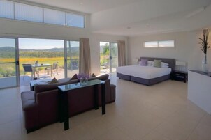 A spacious bedroom with a large bed, a glass dining table, and a sofa.