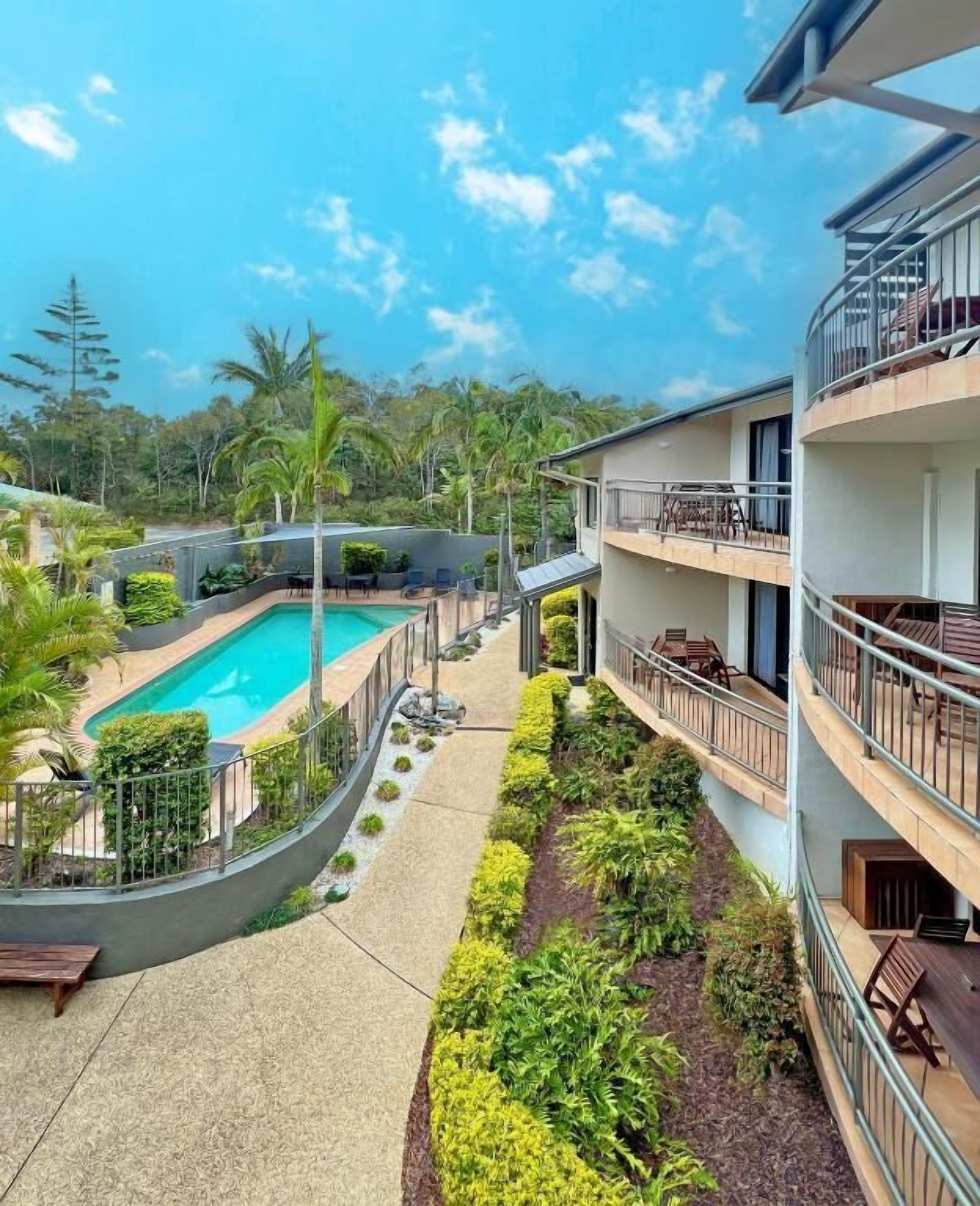 A hotel with a pool, outdoor seating, and a garden area.