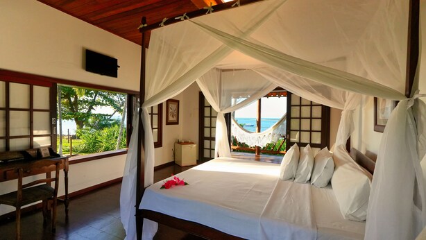 Een slaapkamer met een bed, een bureau en uitzicht op zee.