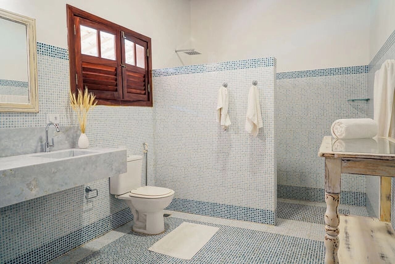 Un baño con lavamanos de mármol, inodoro, zona de ducha y tocador de madera.