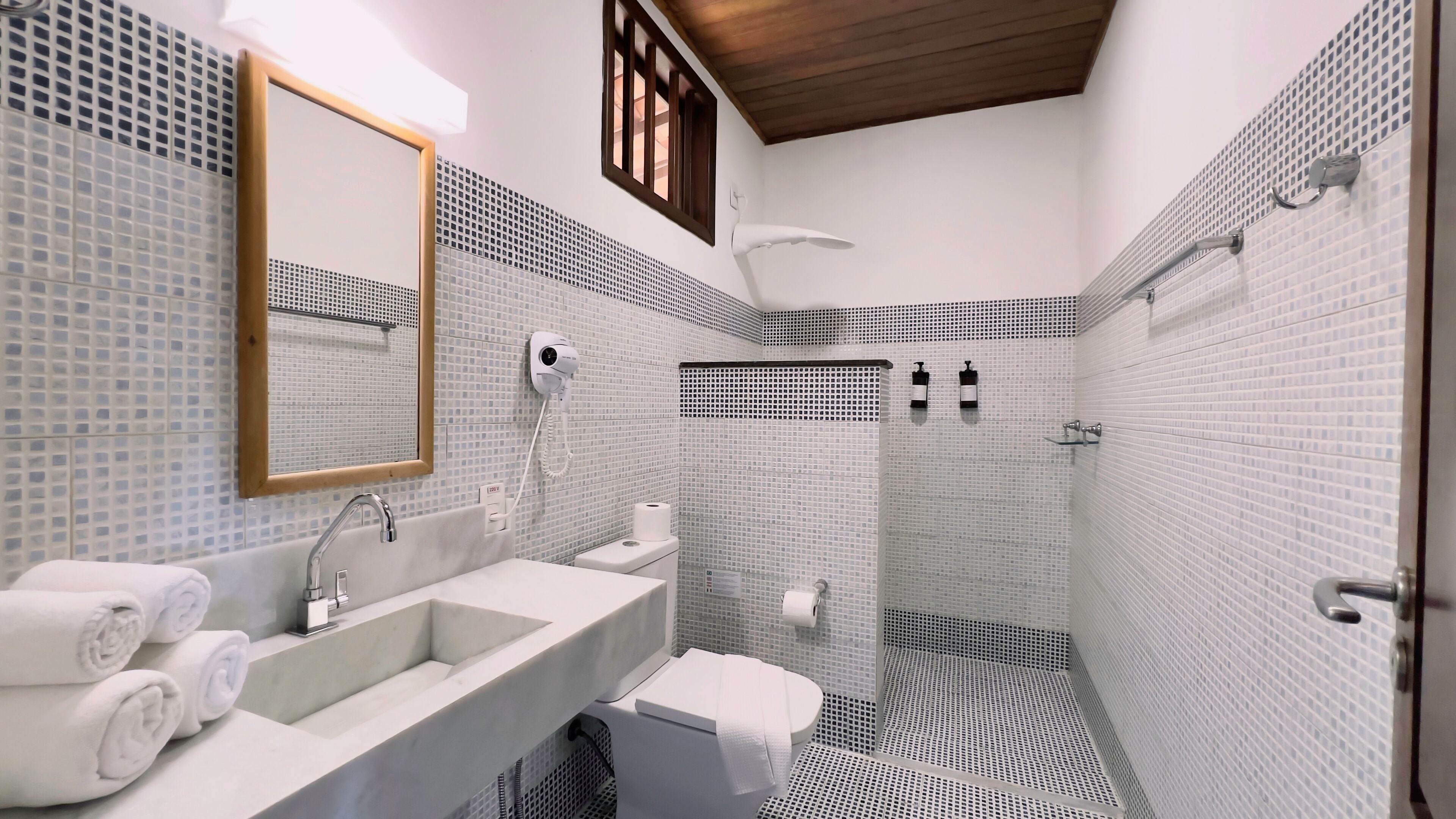 A bathroom with a sink, mirror, towel rack, toilet, and shower.