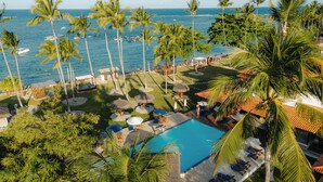 Een resort met een zwembad, palmbomen en uitzicht op de oceaan.