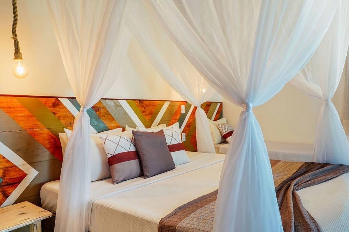 A bed with a canopy, pillows, and a headboard with a geometric pattern.