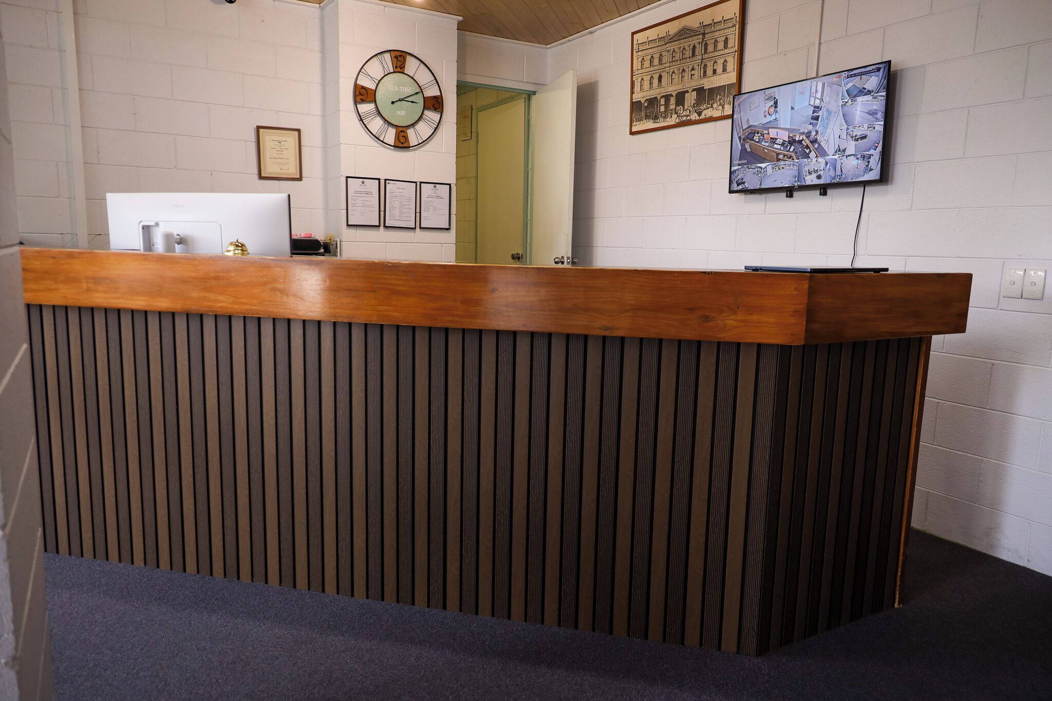 A reception desk with a clock, framed certificates, and a security camera on the wall.