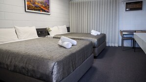 A hotel room with two beds, a desk, and a cityscape painting on the wall. - Bendigo Motor Inn (Kangaroo Flat)