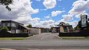 A hotel entrance with a clear sky, a parking lot, and a sign for 'Bendigo Motel Inn'.