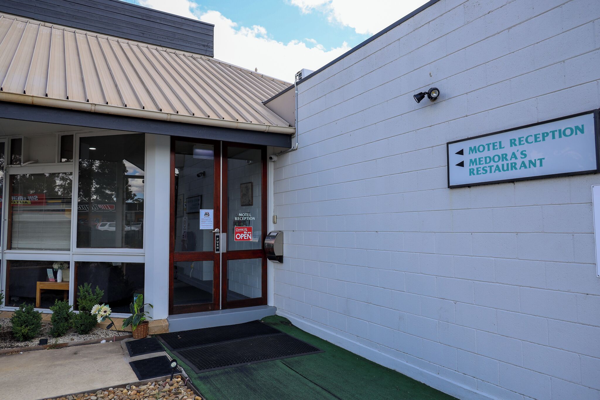 A motel reception with a sign indicating directions to the motel and Medora's restaurant.