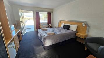 A hotel room with a bed, a desk, a chair, and a small table.