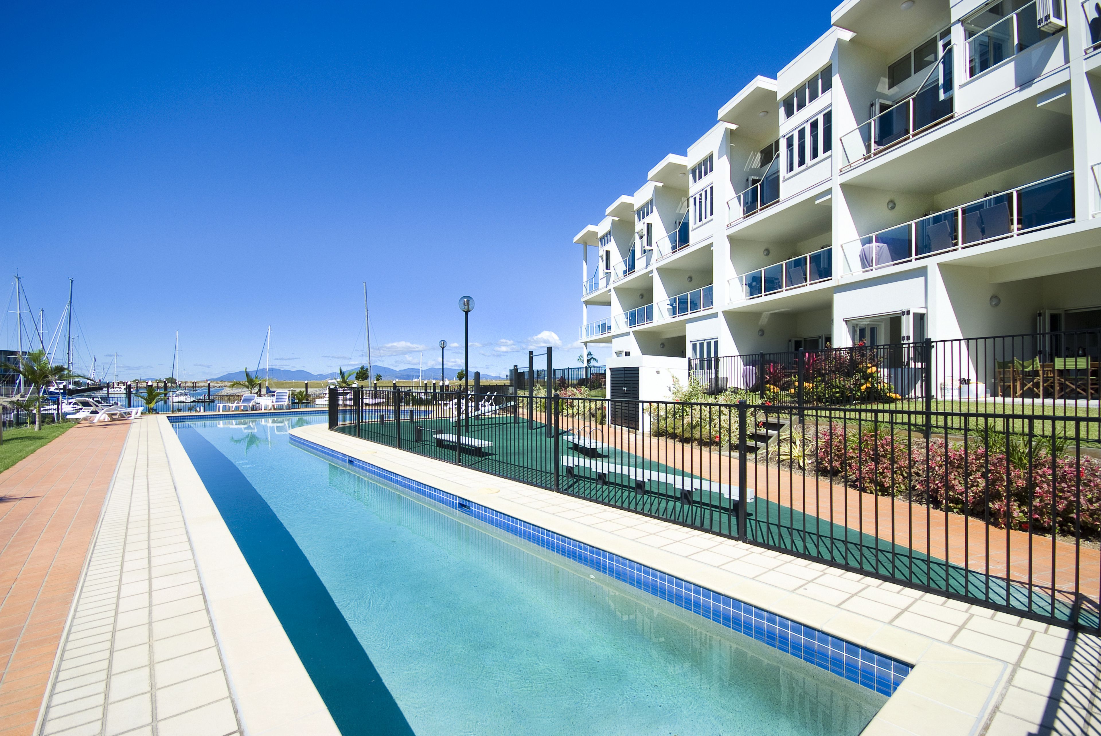Une piscine située à côté d’un immeuble à plusieurs étages doté de balcons.
