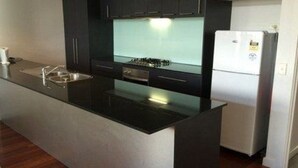 Una cocina moderna con encimera negra, electrodomésticos de acero inoxidable y horno empotrado.