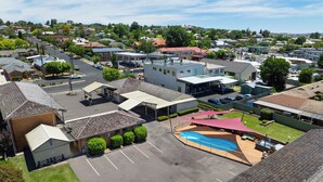 Vista aérea de una zona residencial con piscina, aparcamiento y varios edificios, incluyendo una gasolinera.