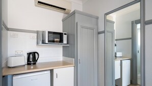 Una kitchenette compacta equipada con microondas, tostadora y refrigerador pequeño.