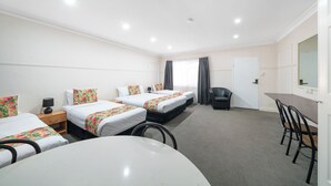 Habitación de hotel con dos camas, un escritorio, una silla y una mesita.