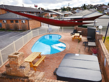 Una piscina al aire libre, sillones reclinables de piscina
