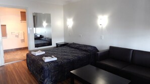 A hotel room with a bed, a sofa, a small table, and a mirror. - Blackwater Hotel Motel (Blackwater)