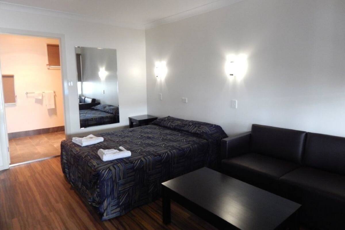 Una habitación de hotel con cama, sofá, una mesita y un espejo.