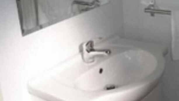 Une salle de bain avec un lavabo blanc, un miroir et des armoires.