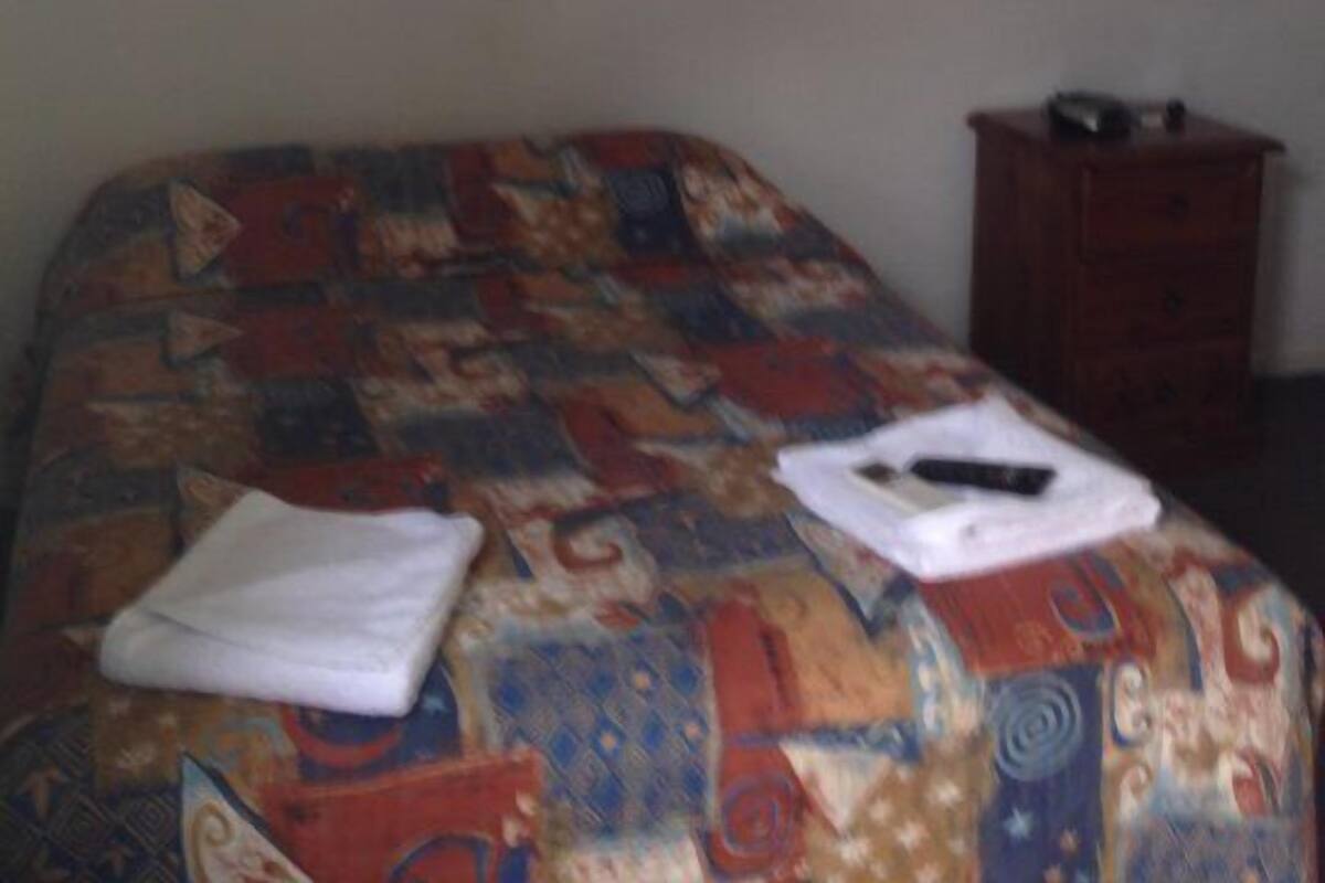 Una habitación de hotel con cama, cómoda y aire acondicionado de pared.