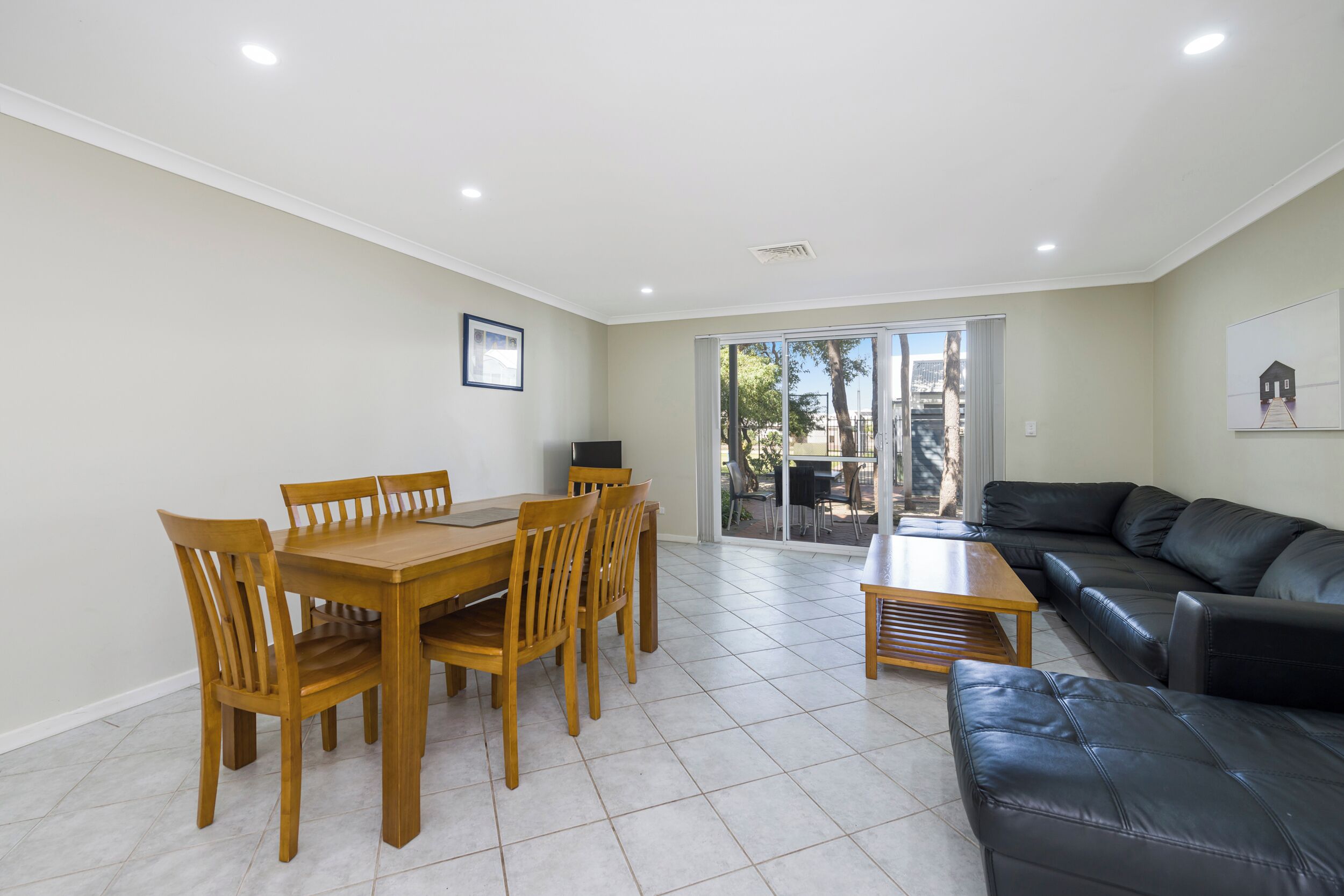 A living room with a dining table, chairs, a sofa, and a TV.