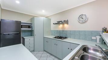 Una cocina moderna con refrigerador de acero inoxidable, microondas, estufa a gas y pileta doble.