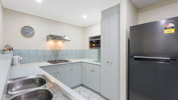 Una cocina moderna con electrodomésticos de acero inoxidable, un reloj y un refrigerador Samsung.