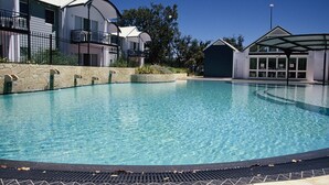 En pool med klart vatten, en mur av sten och ett staket av metall.