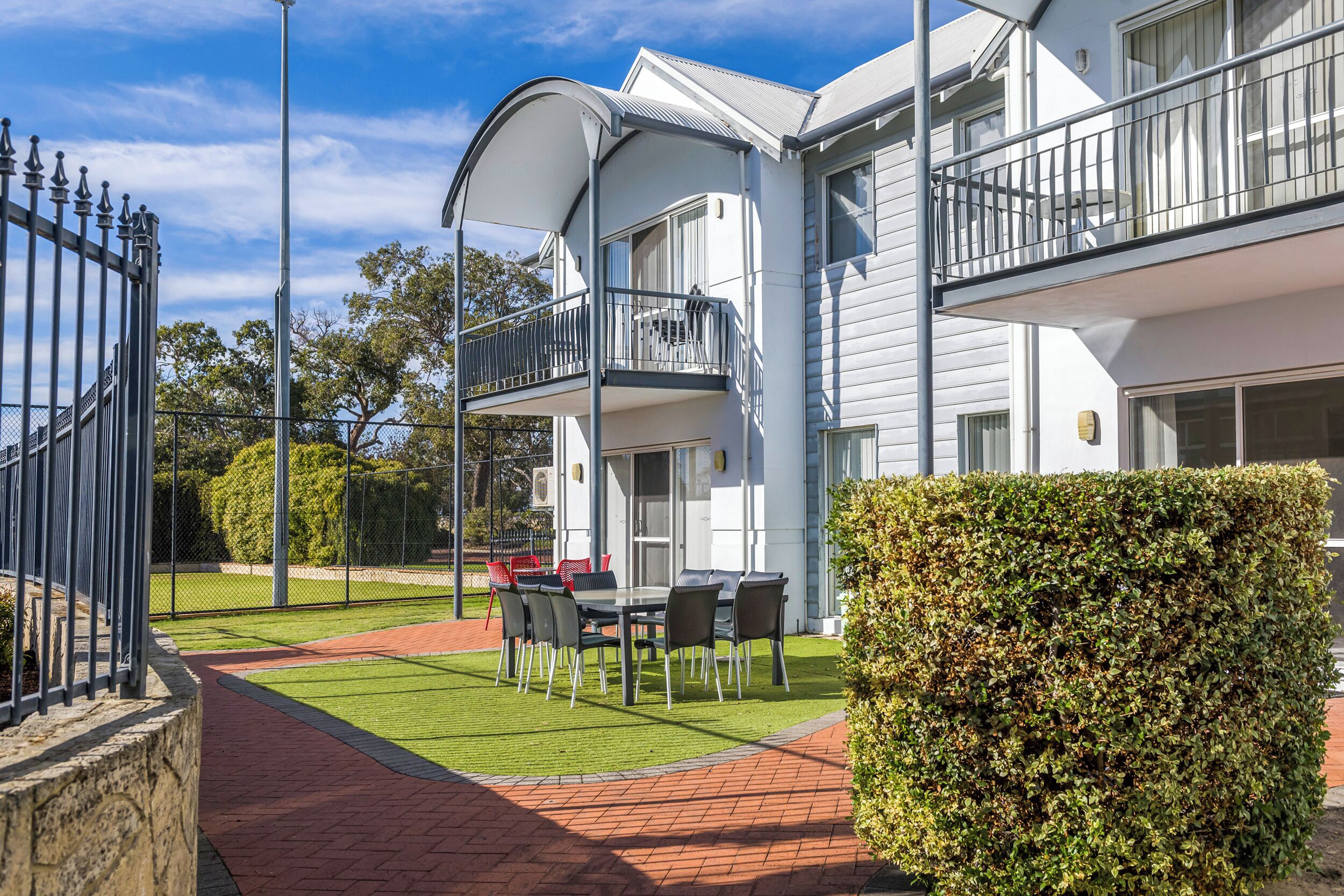 A modern building with a balcony, a paved patio, and a well-maintained lawn.
