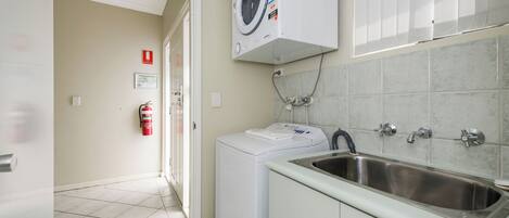 A laundry area with a washing machine, a sink, and a fire extinguisher.