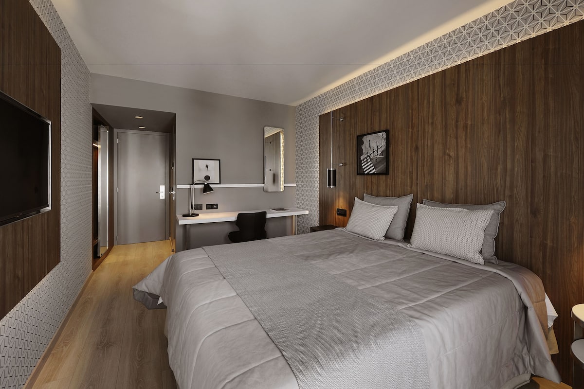 Een moderne slaapkamer met een groot bed, een bureau en een spiegel.