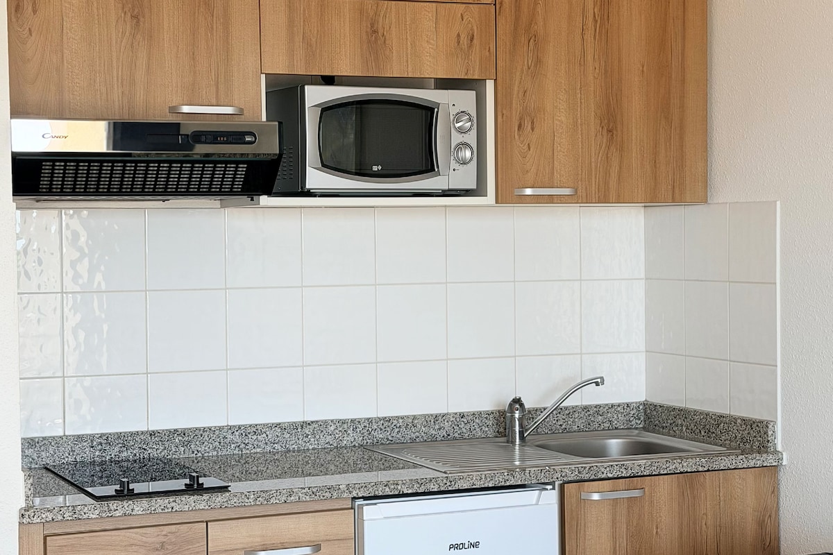 A kitchen with wooden cabinets, a microwave, a dishwasher, and a granite countertop.