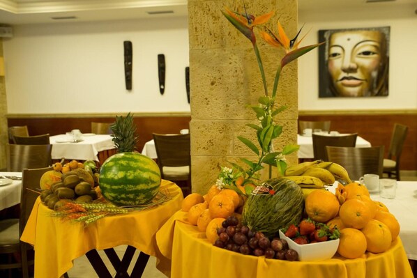 A dining area with tables set for meals, featuring a variety of fruits and vegetables.