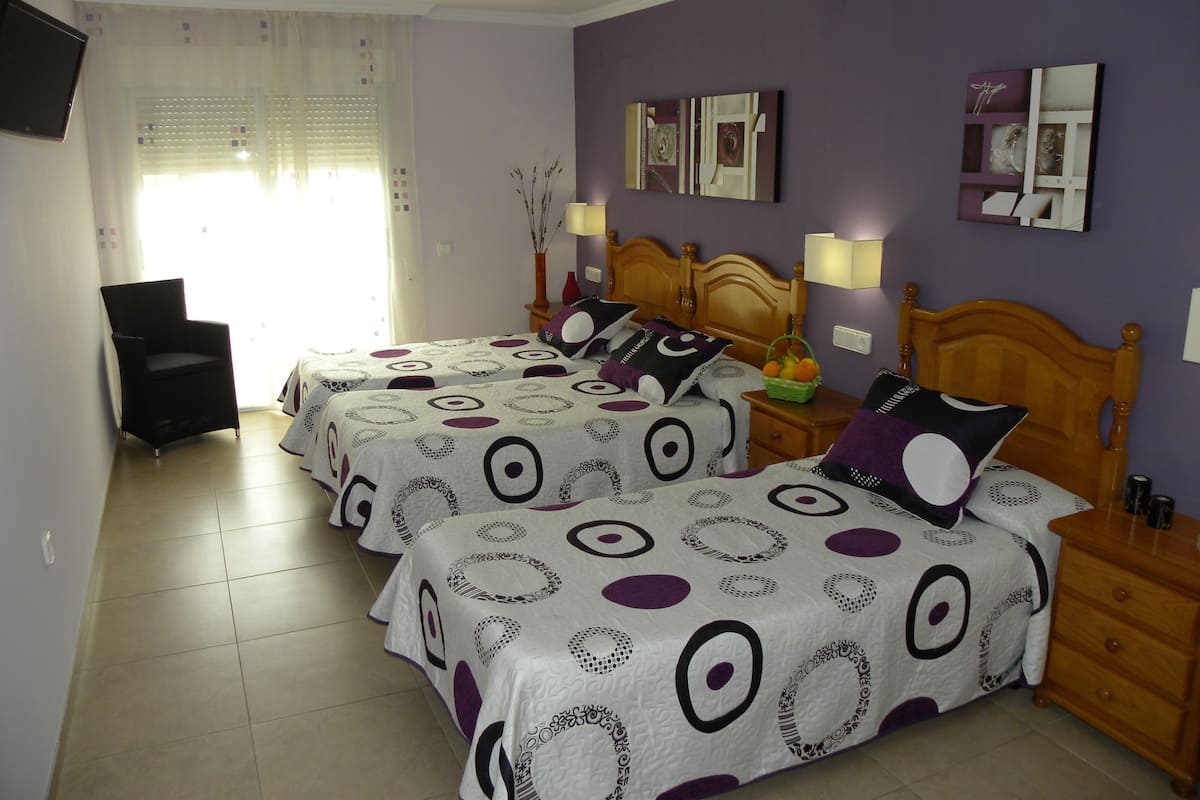 Une chambre avec deux lits, une chaise et une table de chevet avec une lampe.