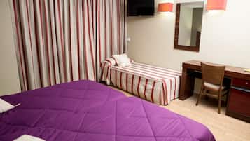 A hotel room with a large bed, a smaller bed, a desk, a chair, a TV, and a mirror.