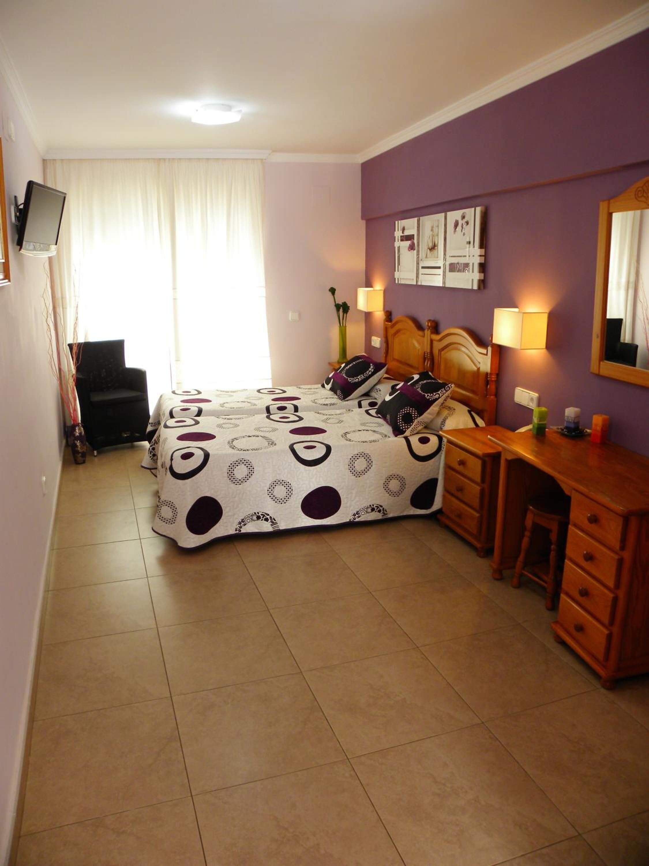 A bedroom with a bed, a desk, and a chair.