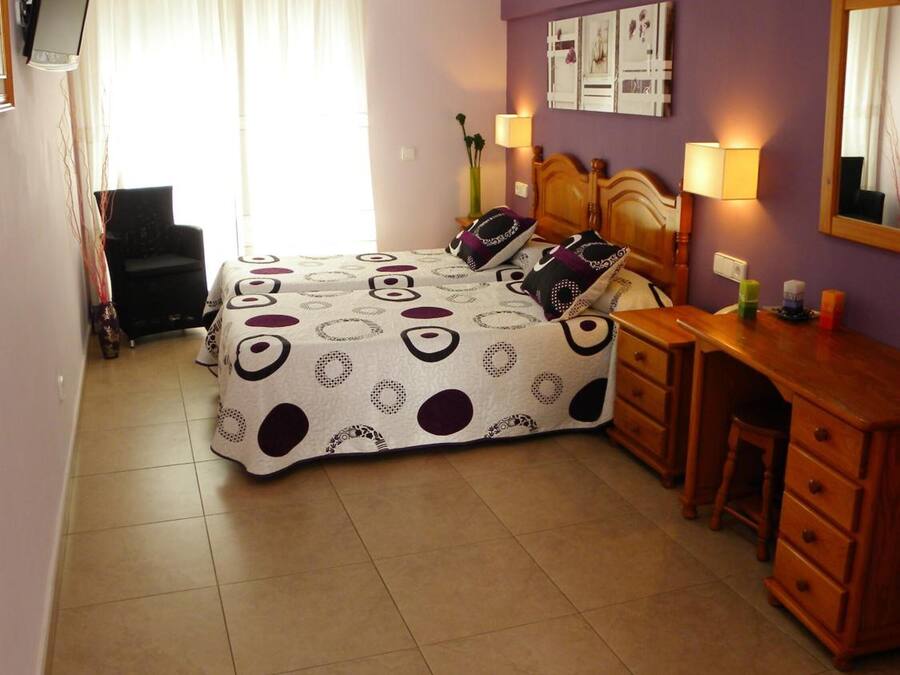 A bedroom with a bed, a desk, and a chair.